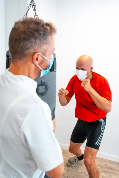 Fisioterapeuta Con Máscara Sosteniendo Saco Boxeo Para Que Paciente Golpee —  Fotos de Stock