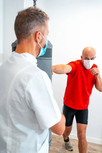 Fysioterapeutti Maskilla Yhdessä Potilaan Kanssa Nyrkkeilysäkissä Fysioterapia Suojatoimenpiteet Coronavirus Pandemian — kuvapankkivalokuva