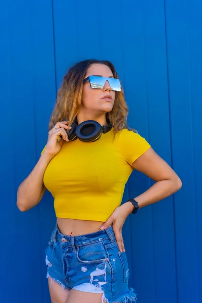 여자노란 티셔츠를 배경의 관능적 시선으로 헤드폰과 선글라스를 — 스톡 사진