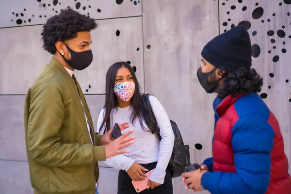 ライフスタイル 3人の黒いラテン系の友人が通りで話しており フェイスマスクで楽しんでいます コロナウイルスのパンデミックにおける友情 Covid 社会的距離社会的責任新しい普通 — ストック写真