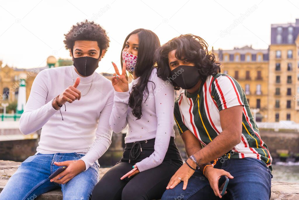 Lifestyle, portrait of three black Latino friends having fun in the street with face masks. Friendships in the coronavirus pandemic, covid-19. Social distance, social responsibility, new normal