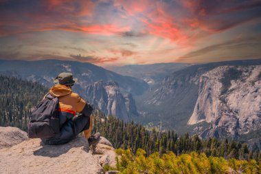 Yosemite Ulusal Parkı 'ndaki Sentinel Dome' da oturan genç bir adam El Capitan Dağı 'na bakıyor. Birleşik Devletler
