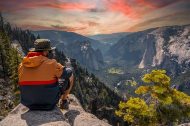 Yosemite Ulusal Parkı 'ndaki Sentinel Dome' da oturan genç bir adam El Capitan Dağı 'na bakıyor. Birleşik Devletler