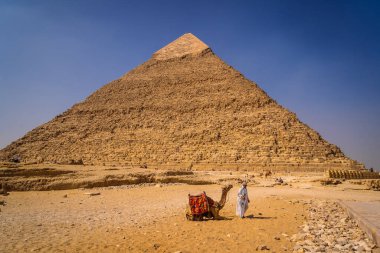 Kahire, Mısır; Ekim 2020: Khafren Piramidi 'nde bir adamla oturan bir deve. Giza Piramitleri dünyanın en eski cenaze anıtı.
