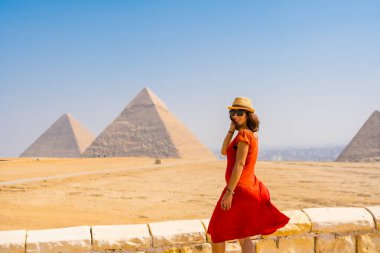 Giza Piramitleri 'nde kırmızı elbiseli bir turist kız. Dünyanın en eski cenaze anıtı. Mısır 'ın Kahire şehrinde
