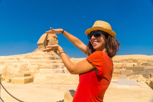 ギザの大スフィンクスと世界最古の葬儀記念碑であるギザのピラミッドを背景に冗談を言う赤いドレスの若い観光客 エジプトのカイロでは — ストック写真