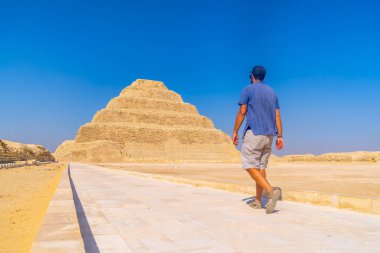 Djoser, Saqqara Basamaklı Piramidi 'nde yürüyen genç bir adam. Mısır. Memphis 'teki en önemli mezarlık. Dünyanın ilk piramidi.