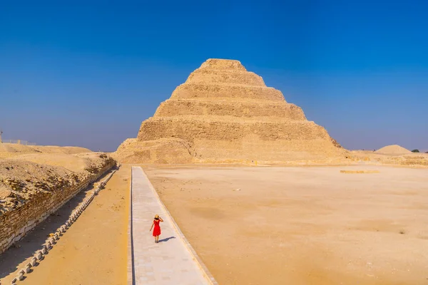 Kırmızı elbiseli genç bir kadın Djoser Piramidi, Saqqara 'yı ziyaret ediyor. Mısır. Memphis 'teki en önemli mezarlık. Dünyanın ilk piramidi.