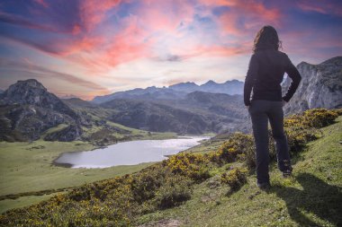 Asturias 'taki güzel Covadonga Gölü' ne bakan genç bir kadın güzel bir bahar günbatımında, Picos de Europa. İspanya