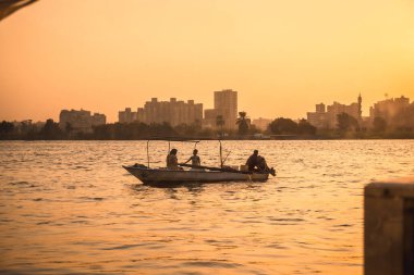 Günbatımında Nil nehrinde Kahire şehrinin arka planında yerel bir balıkçı ailesi. Afrika