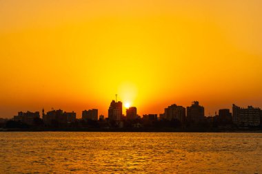 Nil nehrinde portakal rengi günbatımı, arka planda Kahire şehrinin binalarında gizlenen güneş. Afrika