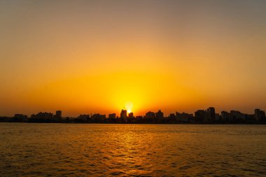 Nil nehrinde portakal rengi günbatımı, arka planda Kahire şehrinin binalarında gizlenen güneş. Afrika