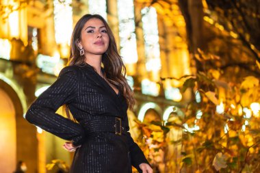 Noel çekimleri, beyaz tenli genç bir esmerin Noel 'de şehir ışıklarının tadını çıkarırken çekilmiş gece fotoğrafı. Zarif siyah noel ya da yeni yıl elbisesi