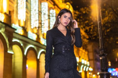 Noel çekimi, şehirde güzel bir esmer kız güzel bir binanın Noel ışıklarının yanında. Zarif siyah Noel ya da siyah çizmeli yeni yıl elbisesi