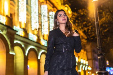 Noel çekimi, şehirde güzel bir esmer kız güzel bir binanın Noel ışıklarının yanında. Zarif siyah Noel ya da siyah çizmeli yeni yıl elbisesi