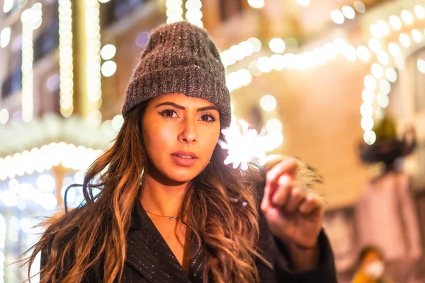 Noel 'de şehrin güzel bir binasında Noel ışıkları, geceleri elinde meşalelerle beyaz bir kadın. Kış şapkasıyla