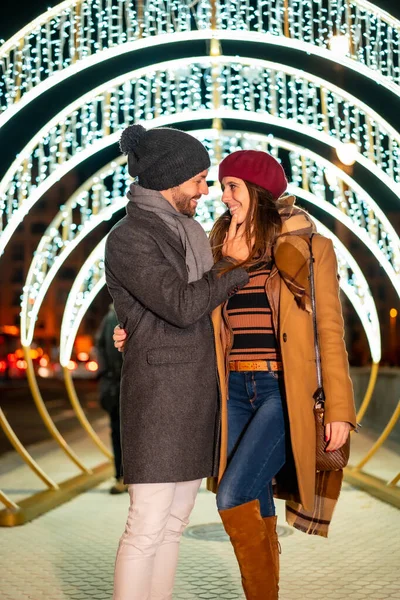 Romantic winter gaze of a Caucasian couple next to the christmas lights of the city, lifestyle