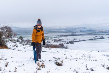 Sarı ceketli genç kız karda şemsiyeyle oynuyor. Araba, Bask ülkesinin Vitoria yakınlarındaki Opakua kasabasında kar. İspanya