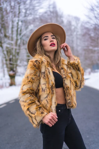 冬天的生活方式 模特穿着内衣裤 头戴牛仔帽 身穿豹纹毛衣 站在马路中央 背景是冰冻的树木 — 图库照片