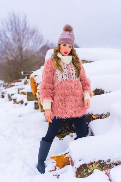 Pozowanie Blond Modelki Różowym Futrze Fioletowym Kapeluszu Śniegu Obok Drzew — Zdjęcie stockowe