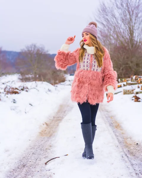 Młoda Blondynka Różowym Futrze Fioletowym Kapeluszu Śniegu Spacer Śnieżnej Ścieżce — Zdjęcie stockowe