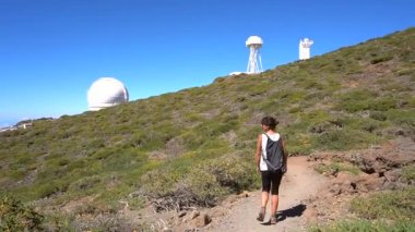 Bir yaz öğleden sonra, Roque de los Muchachos yakınlarındaki Caldera de Taburiente volkanının tepesindeki teleskopların rotasında genç bir kadın, La Palma, Kanarya Adaları. İspanya