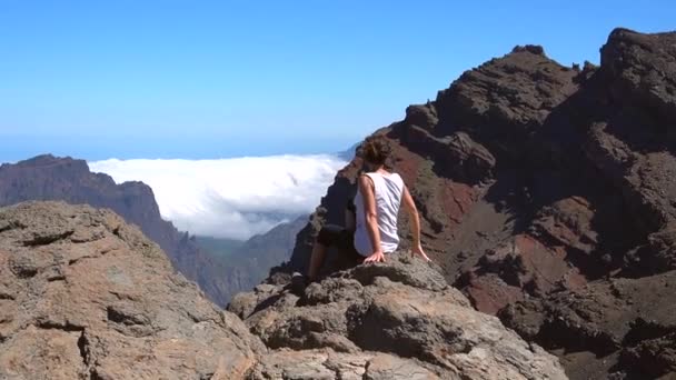 一个夏日的下午 在加那利群岛拉帕尔马 一名年轻妇女坐在罗克德洛斯穆查科斯附近的卡尔德拉塔布连火山顶上 西班牙 — 图库视频影像