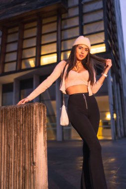 Şehirde kışın pembe yün şapka ve süveter giyen genç seksi Kafkas esmer portresi. Sokak modası