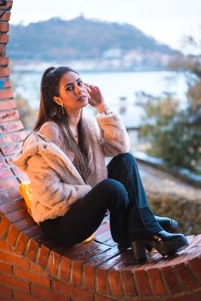 高加索黑发模特坐在冬季与城市为背景 街头时尚 — 图库照片