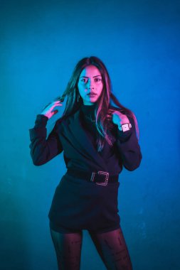 Mavi ve pembe neonlarla aydınlatılmış genç Kafkas modelinin portresi. Mavi bir duvar arkaplanında