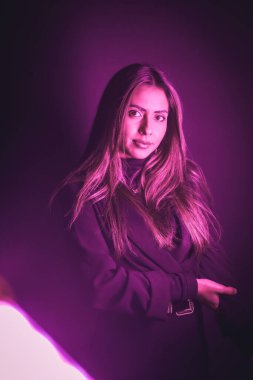 Pembe neon ışıklarla aydınlatılmış genç beyaz modelin portresi. Siyah bir duvar arka planında