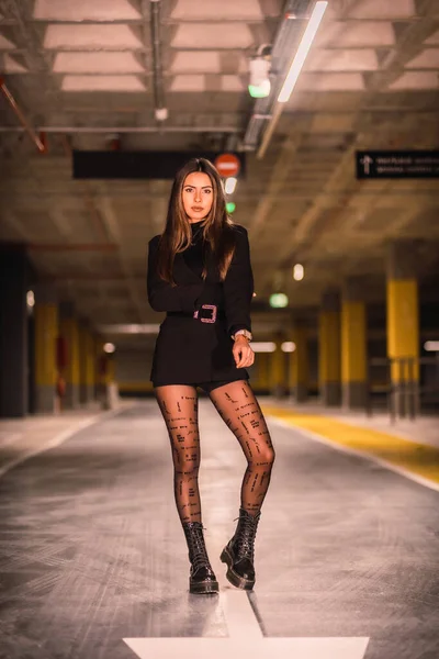 年轻的高加索模特儿 黑色夹克摆设在一个空的地下停车场里 城市夜市会议 — 图库照片