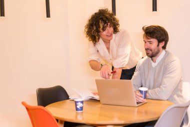 Ofiste yaşam tarzı, ofiste kadın patron ve genç işçi, bir bilgisayar ve bir not defteriyle.