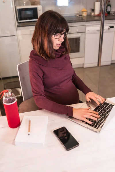 由于工作困难 年轻孕妇在家用电脑远程工作 在视频会议上做了笔记 — 图库照片