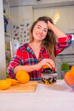 Sağlıklı bir yaşam tarzı, portakal sıkan sarışın beyaz bir kadının portresi taze portakal suyu yapıyor.