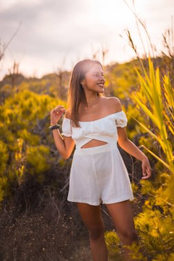 Beyaz elbiseli, kumsal tatilinin tadını çıkaran esmer bir kadının yaşam tarzı.