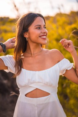 Beyaz elbiseli, kumsal tatilinin tadını çıkaran esmer bir kadının yaşam tarzı.