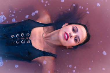 Yazın Torrevieja 'nın pembe gölünde tatilde olan genç esmer bir beyazın pozu. Suda uzanıp kameraya bakıyor, Alicante. İspanya