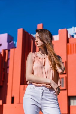 Somon rengi gömlekli, beyaz pantolonlu, mavi gökyüzü yaz sabahı dikey fotoğraflı beyaz bir kadının yaşam tarzı.