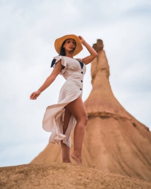 Bardenas Reales çölünün Castildetierra 'sında beyaz elbiseli ve hasır şapkalı esmer bir kız, Navarra. İspanya