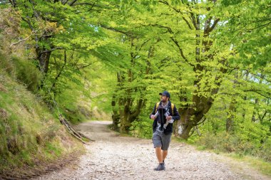 Yeni doğmuş çocuğuyla birlikte ormanda bir patikada ailesiyle pikniğe giden genç bir baba.