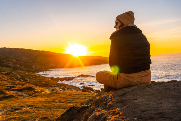 A young woman with a wool cap relaxed in winter watching the sunset on the Jaizkibel mountain in the town of Pasajes, Gipuzkoa. Basque Country