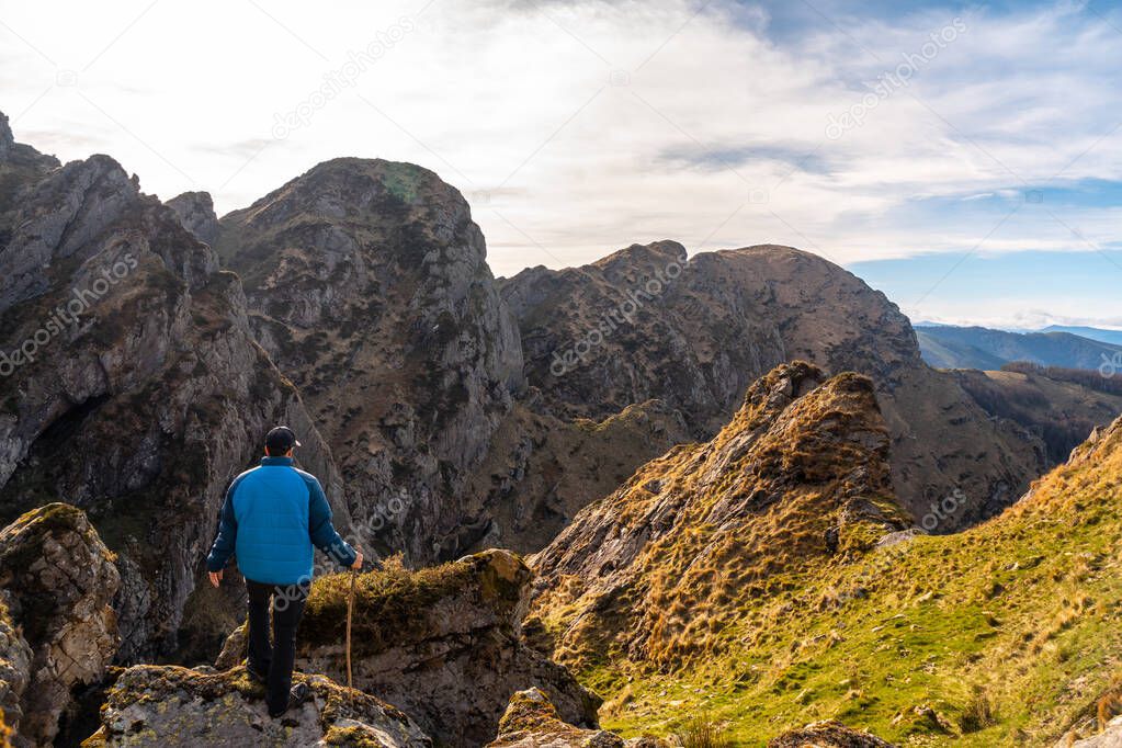 A young man in a gray sweater looking at the views of the towns of Hondarribia and Hendaya from the mountains of Aiako Harria or Penas de Aya, Guipzcoa. Basque Country