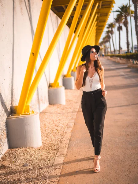 Lifestyle Una Joven Morena Tacones Pantalones Sombrero Negro Paseo Amarillo — Foto de Stock