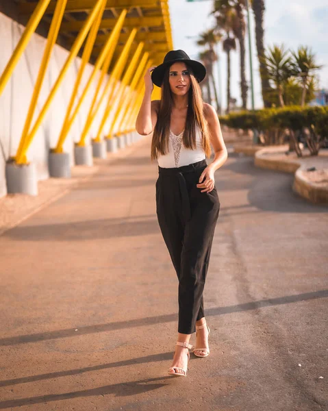 Lifestyle Young Brunette Walking Mediterranean Heels Pants Black Hat Yellow — 스톡 사진