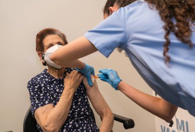 San Sebastian, Gipuzkoa. İspanya. 8 Mayıs 2021: Korkmuş yaşlı bir kadın aşı merkezinde genç bir hemşire tarafından iğne vuruluyor, kovid-19. Coronavirüs