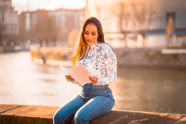 川の本を読んで日没時に街のブルネットのラテン語の少女 楽しい女の子のライフスタイル — ストック写真
