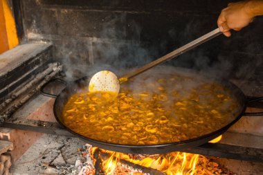 Valensiyalı paella 'nın pirincini közle ve sebzeyle karıştırıyorum. Geleneksel İspanyol yemeği, balık ve deniz ürünleri paella