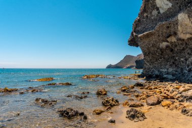 Cabo de Gata Doğal Parkı 'ndaki Monsul plajı çevresini saran lav oluşumları, ince kum ve kristal berrak su. San Jose, Almerya. İspanya