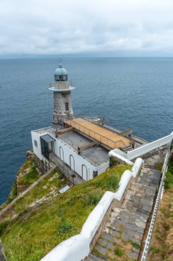 Santa Catalina de Lekeitio deniz feneri bulutlu bir bahar sabahı, arka planda deniz, Bizkaia manzarası. Bask Ülkesi